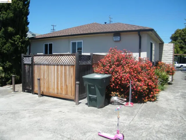 Rear exterior featuring a brown shingle roof, stucco siding, and multiple windows
