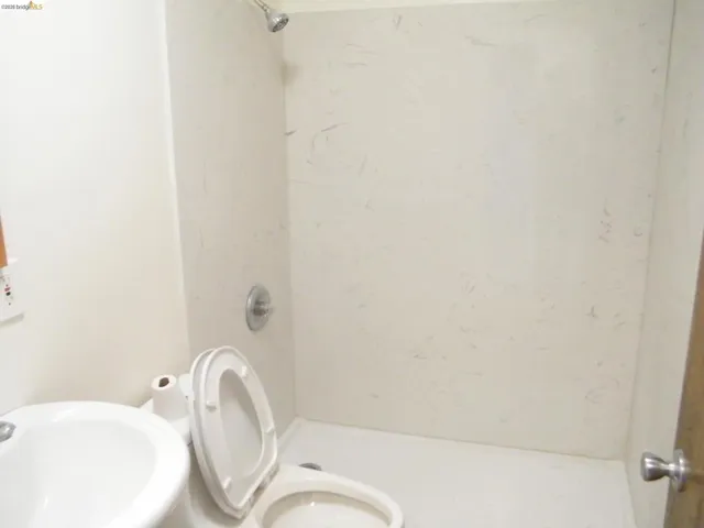Shower stall with a single showerhead, chrome fixtures, and a white, textured surround