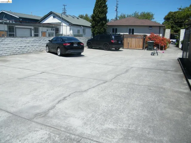 Expansive concrete parking pad bordered by a stone retaining wall and privacy fencing