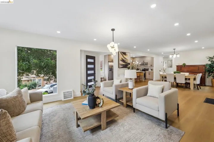 Open-concept living area featuring new vinyl plank flooring, recessed lighting, new entry door with frosted glass panels, and a brand new front picture window.