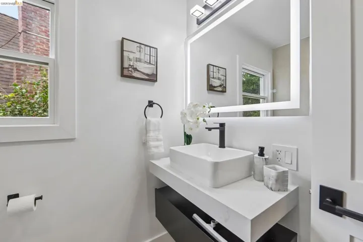 Contemporary bathroom featuring a floating vanity with a rectangular vessel sink, matte black faucet, and an illuminated led mirror
