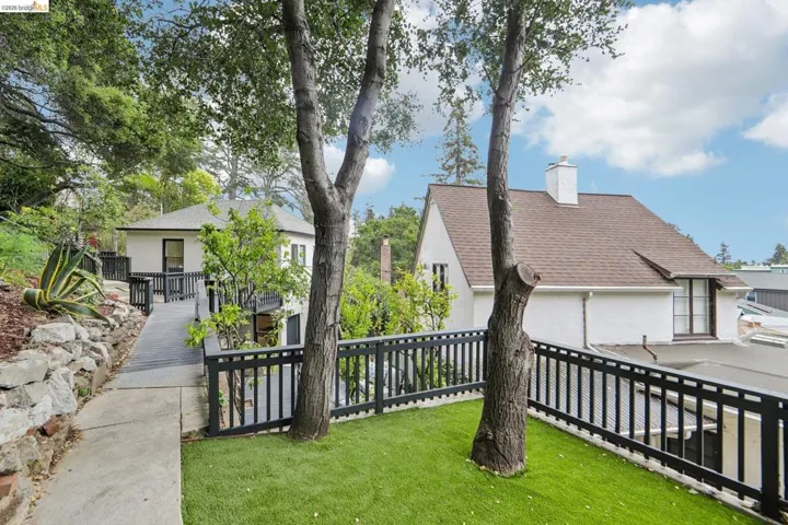Exterior property showcasing a ramp entry and a separate structure, surrounded by mature trees