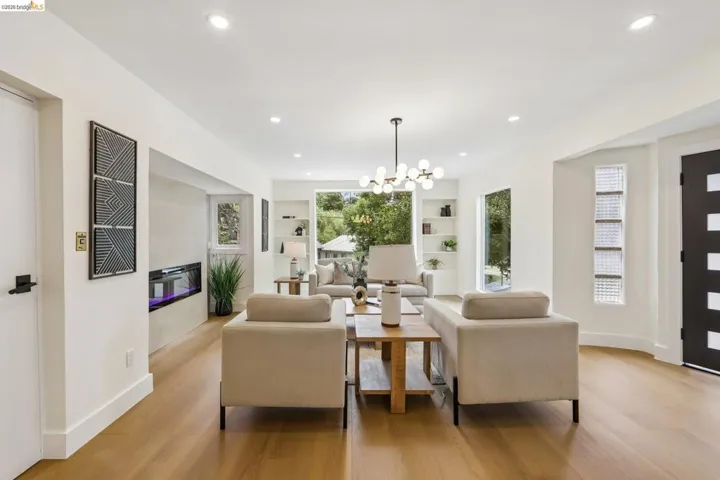 Open-concept living area featuring new vinyl plank flooring, recessed lighting, new entry door with frosted glass panels, new electric fireplace and a brand new front picture window.