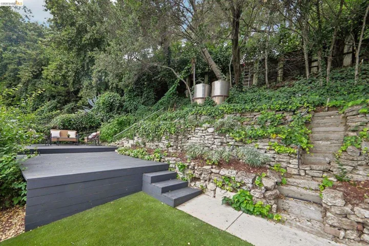 Multi-level outdoor space featuring a dark-stained deck, integrated steps, and a stone retaining wall
