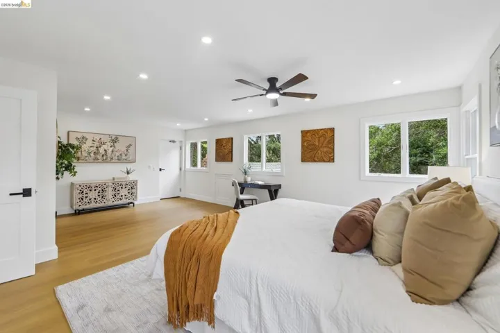 Spacious room featuring vinyl plank flooring, recessed lighting, multiple windows, a ceiling fan, and white flat-panel doors with matte black hardware