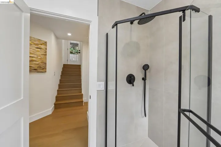 Modern shower enclosure with matte black fixtures, rain shower head, and light-toned tile surround