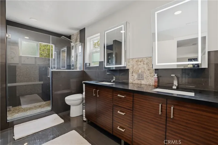 The walk in shower is so elegant with pebble tile accents. Getting ready for your day is a joy with large lighted mirrors.