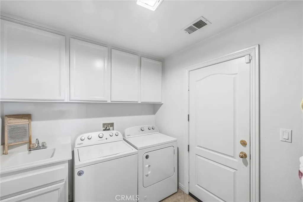 Convenient laundry room with a utility sink, overhead cabinets, and additional storage space. Convenient laundry room with a utility sink, overhead cabinets, and additional storage space.