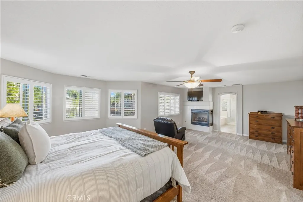 Expansive primary suite featuring plantation shutters, a cozy fireplace, and an inviting sitting area. Expansive primary suite featuring plantation shutters, a cozy fireplace, and an inviting sitting area.