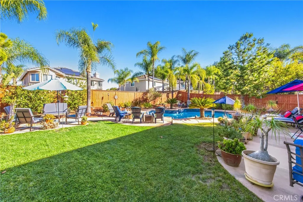 Beautifully landscaped backyard with a spacious lawn, mature palm trees, and multiple seating areas surrounding the sparkling pool. Beautifully landscaped backyard with a spacious lawn, mature palm trees, and multiple seating areas surrounding the sparkling pool.