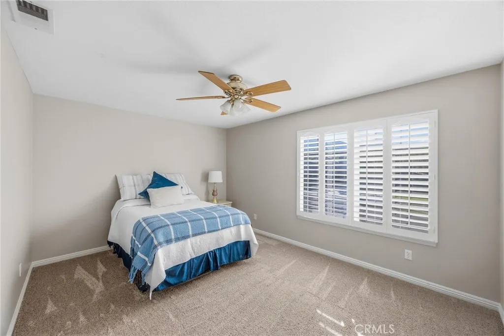 Comfortable bedroom with generous space, soft carpeting, and plantation shutter Comfortable bedroom with generous space, soft carpeting, and plantation shutter