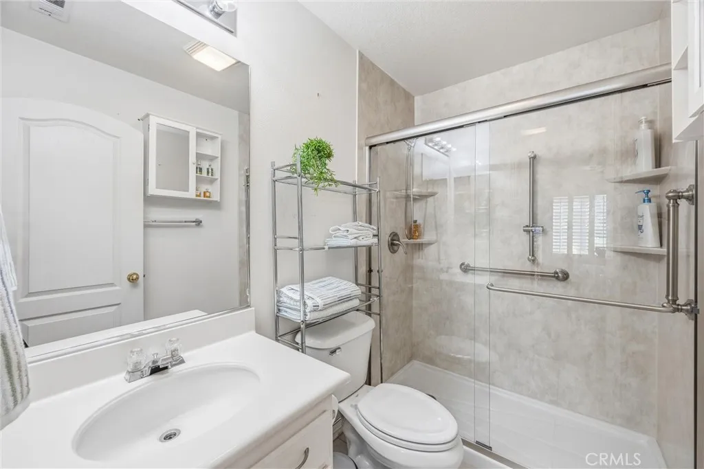 Private downstairs bathroom featuring a walk-in shower with glass doors and built-in shelving. Private downstairs bathroom featuring a walk-in shower with glass doors and built-in shelving.
