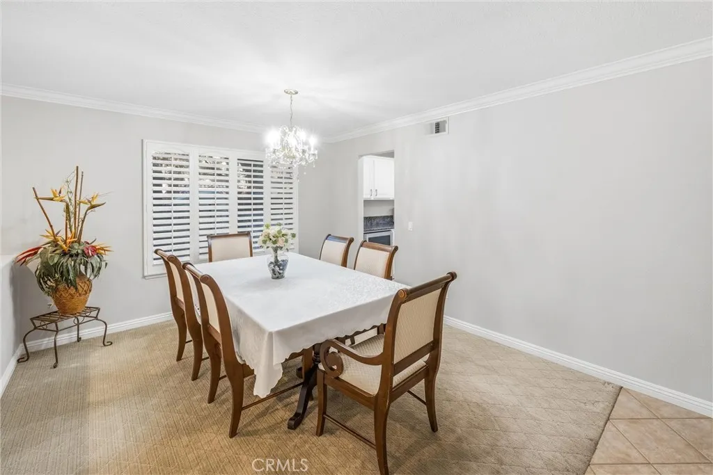 Elegant dining area with a chandelier and plantation shutters. Elegant dining area with a chandelier and plantation shutters.