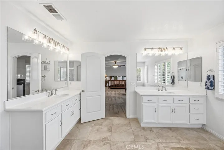 Spacious primary bathroom featuring dual vanities, large mirrors, and plenty of cabinet storage.