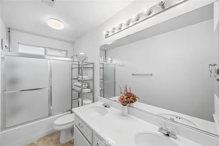 Convenient bathroom featuring a double-sink vanity, generous counter space, and a tub-shower combination.