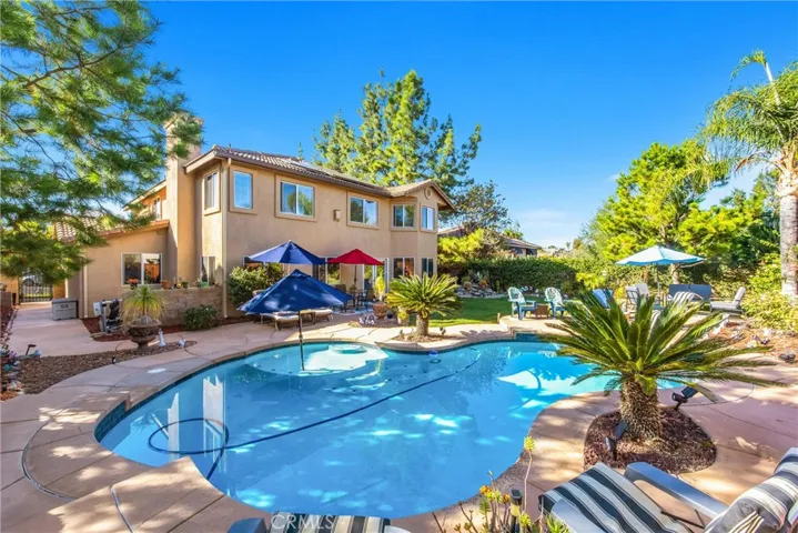 Resort-style backyard with a sparkling pool, relaxing spa, lush landscaping, and inviting spaces for outdoor entertaining.