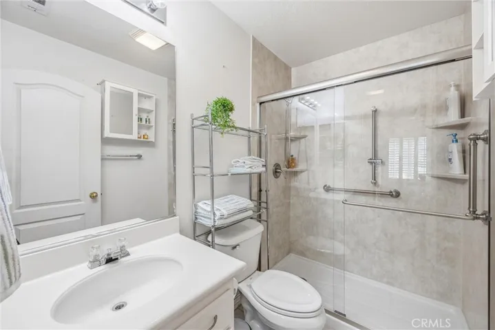 Private downstairs bathroom featuring a walk-in shower with glass doors and built-in shelving.
