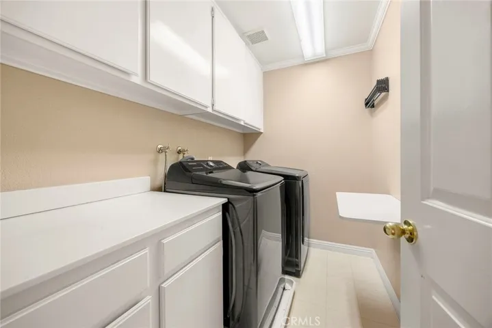 The spacious upstairs laundry room offers generous cabinet storage, a folding counter, and a built-in wall-mounted drying rack for added convenience.
