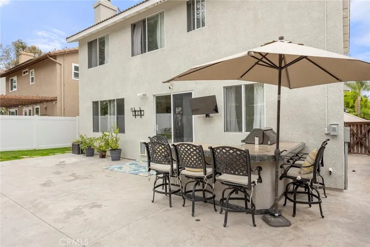 Outdoor entertaining is effortless with the built-in BBQ island featuring bar seating, a mounted TV, and an expansive backyard ready for weekend gatherings.