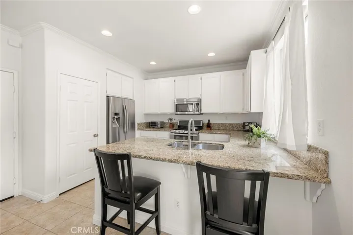 Recessed lighting, a spacious breakfast bar, pantry, and a large window overlooking the backyard make this kitchen ideal for everyday living.
