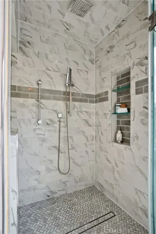 Designer tile and glass enclosed primary shower with multi shower heads and steam system