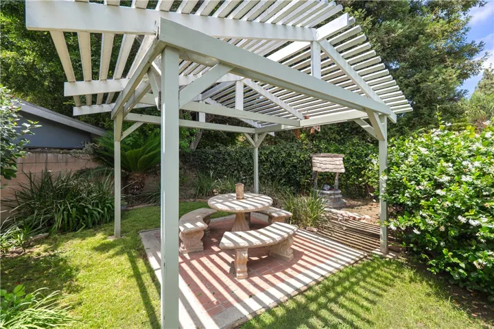 A covered picnic area surrounded by grass and lush shrubs