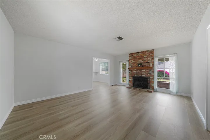 Living room with a cozy brick fireplace. All new Luxury Vinyl Flooring