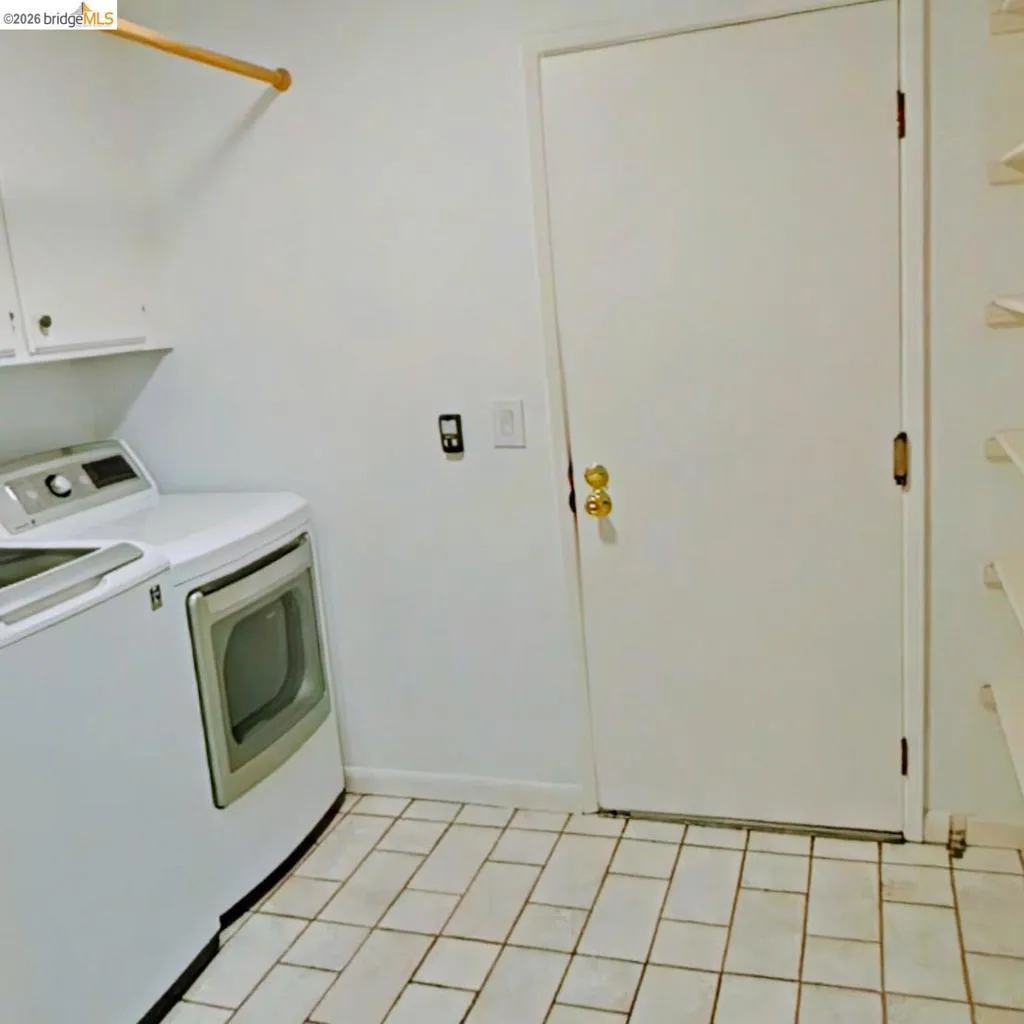 Utility room with tile flooring, wall-mounted cabinetry, and a clothing rod
