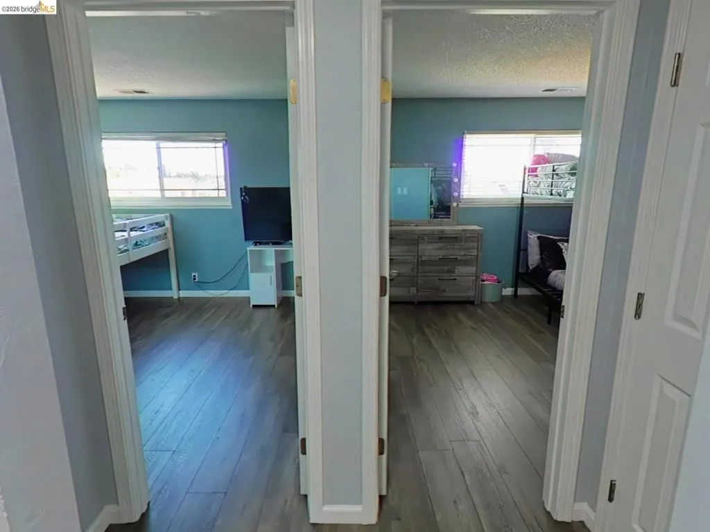 Two rooms featuring wood-finish flooring, light blue wall paint, and white trim