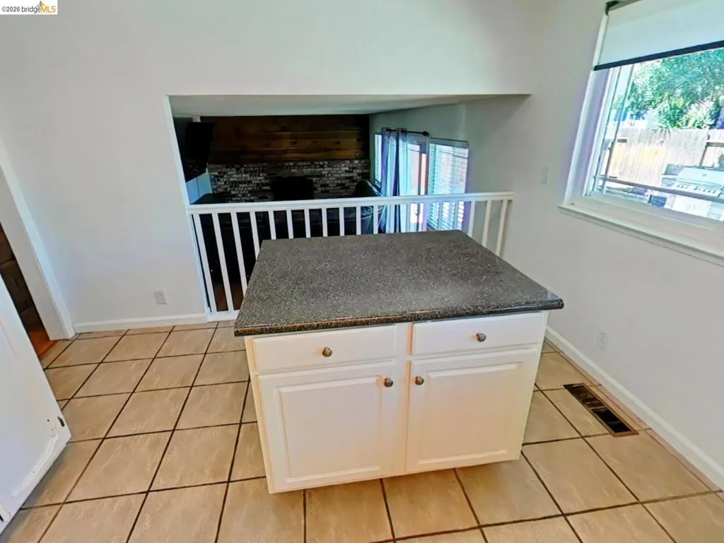 Kitchen area featuring a central island with a speckled countertop and white cabinetry