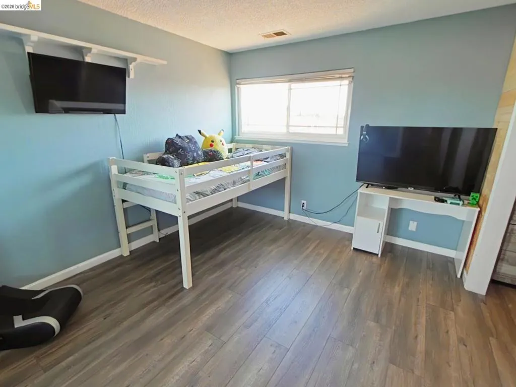 Room with wood-finish flooring, light blue walls, and white trim
