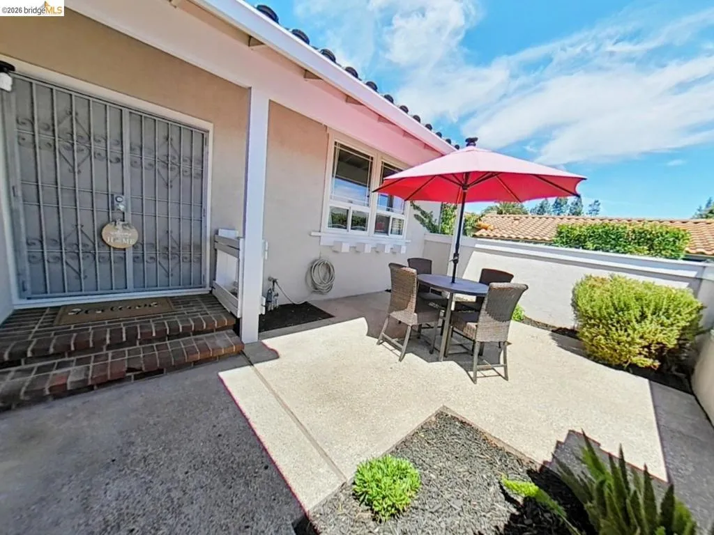 Entry patio featuring concrete paving, brick steps, and a decorative security screen door