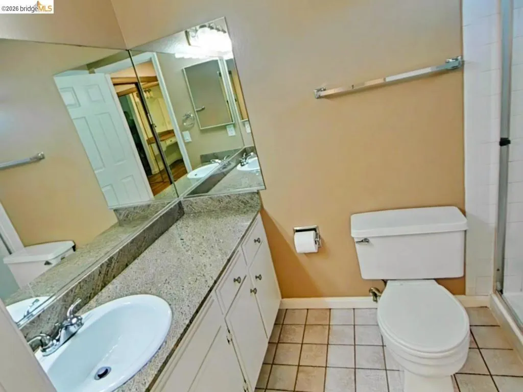 Bathroom vanity featuring a speckled countertop, integrated sink, and white cabinetry