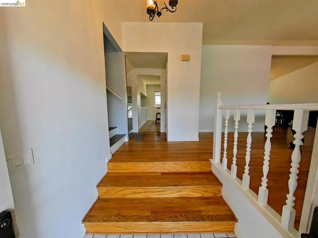 Hardwood stairs with a white spindle railing and an overhead chandelier