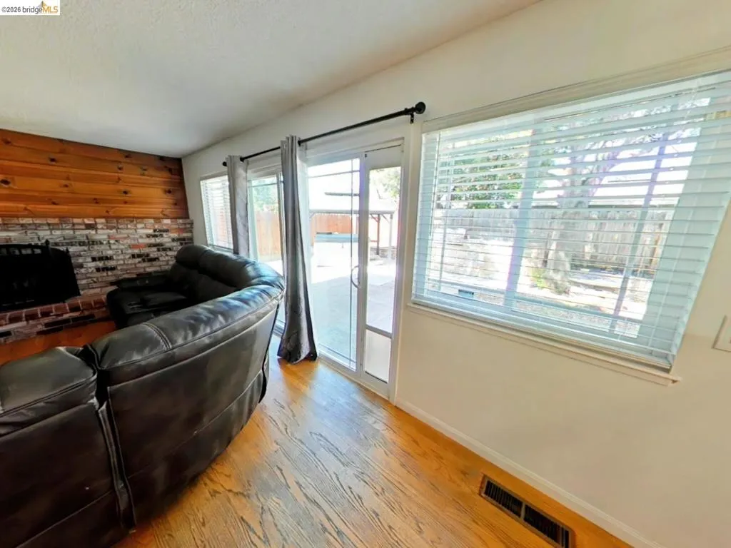 Family area featuring wood-finish flooring, a brick fireplace with a wood accent wall, and a sliding glass door leading to the exterior