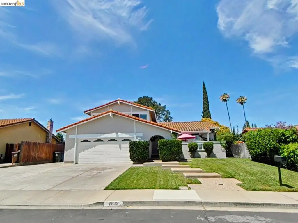 Mediterranean-style residence featuring a terracotta tile roof, attached two-car garage, and a concrete driveway