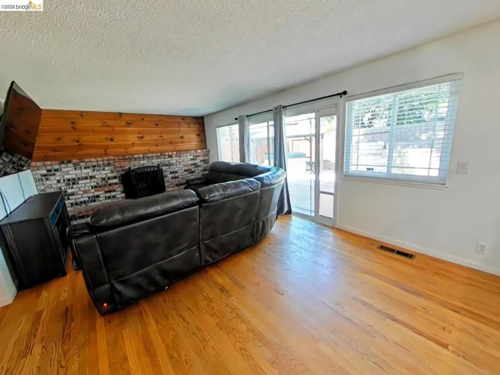 Hardwood flooring and a brick-finish fireplace with a wood paneling accent wall