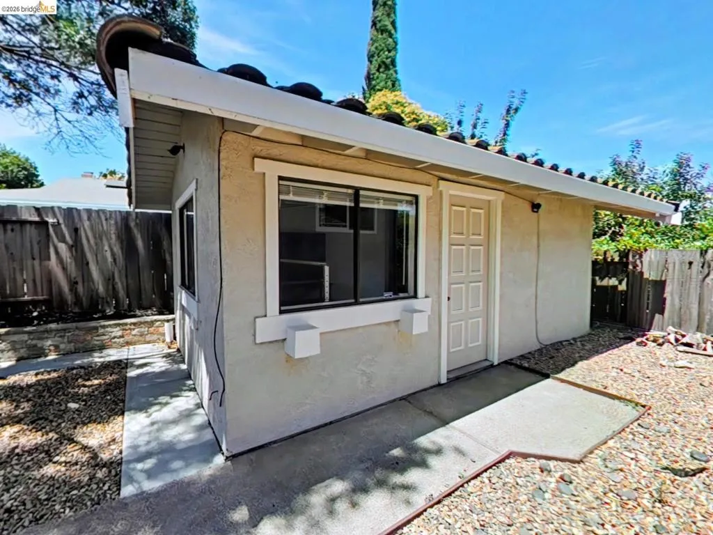 Detached auxiliary structure featuring a stucco exterior, tile roof, and a panel-style door