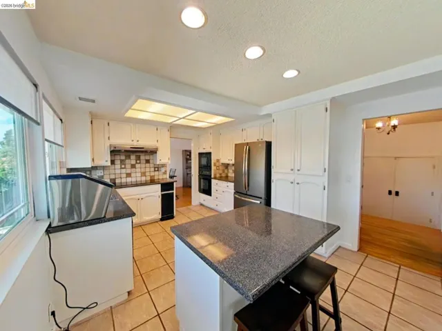 Kitchen featuring white cabinetry, dark speckled countertops, and tile flooring