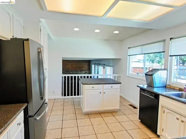 Kitchen featuring stone-look countertops, white cabinetry, a central island with storage, tile flooring, and recessed lighting