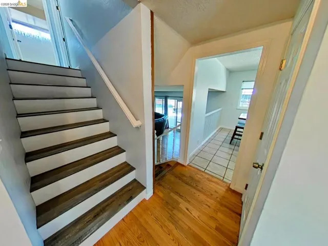 Hardwood flooring in a rich tone, leading to a staircase with wood-finish treads and white risers