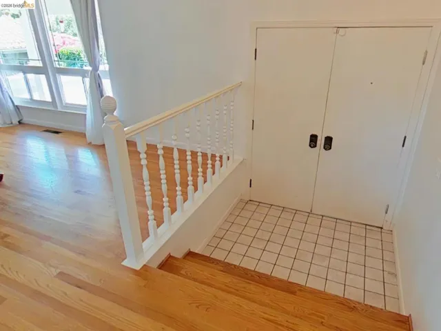 Entryway featuring light wood-finish flooring, white baluster railing, and a tile-floor landing