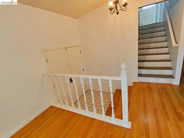 Hardwood flooring throughout the entry, white painted balusters and newel post, and a black wrought iron chandelier
