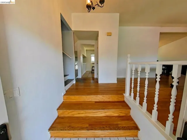 Hardwood stairs with a white spindle railing and an overhead chandelier