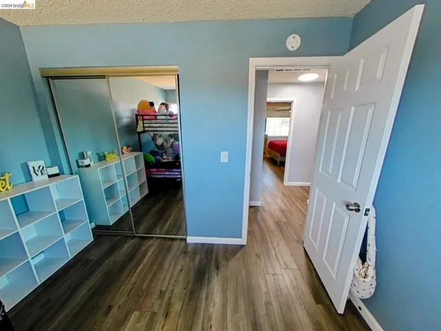 Room featuring wood-finish flooring, a full-length mirrored sliding door closet, and light blue wall paint