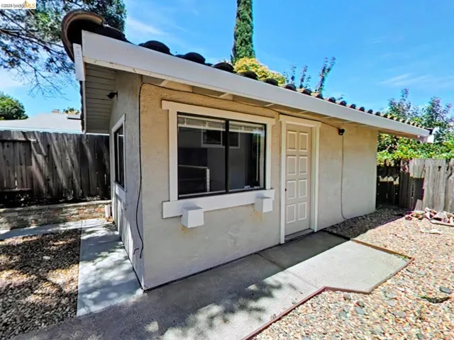 Detached auxiliary structure featuring a stucco exterior, tile roof, and a panel-style door