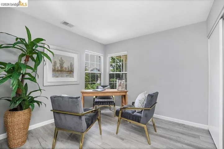 Brightly lit room featuring light gray walls and wood-finish flooring