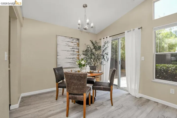 Dining area featuring vaulted ceilings, wood-finish flooring, and a contemporary chandelier