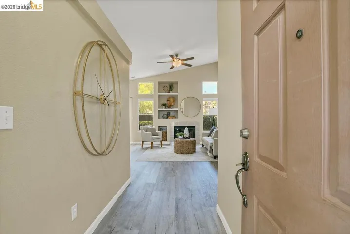 Entryway featuring wood-finish flooring, opening into a living area with a vaulted ceiling