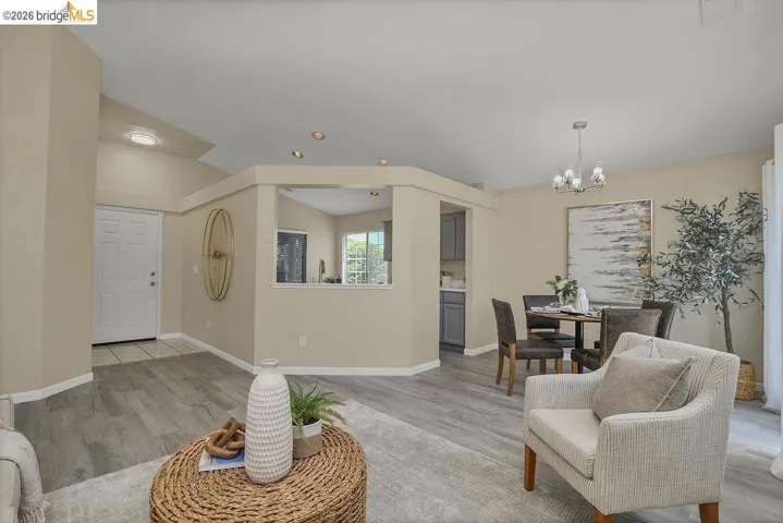 Open-concept living space featuring wood-finish flooring, recessed lighting, and a dining area with a chandelier